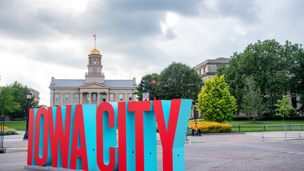 A sign that reads "Iowa City" sits in front of the Old Capitol Building.